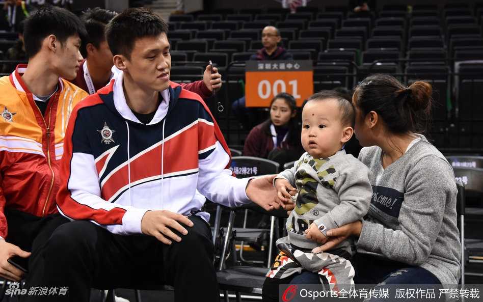 周鹏携家人观战星锐赛,铁血队长的温情一面 周鹏与刘美各抱着一个孩子,孩子们的目光被场内激烈的比赛所吸引,周鹏则微微侧身与妻子交流,仿佛在分享着对某位年轻球员表现的看法