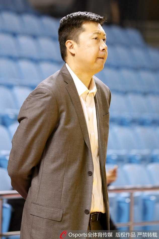 身披教练服的王治郅静立在球场边，眼神专注而沉静，仿佛正在透过场上的激烈对抗，思考着内线进攻的战术变化。