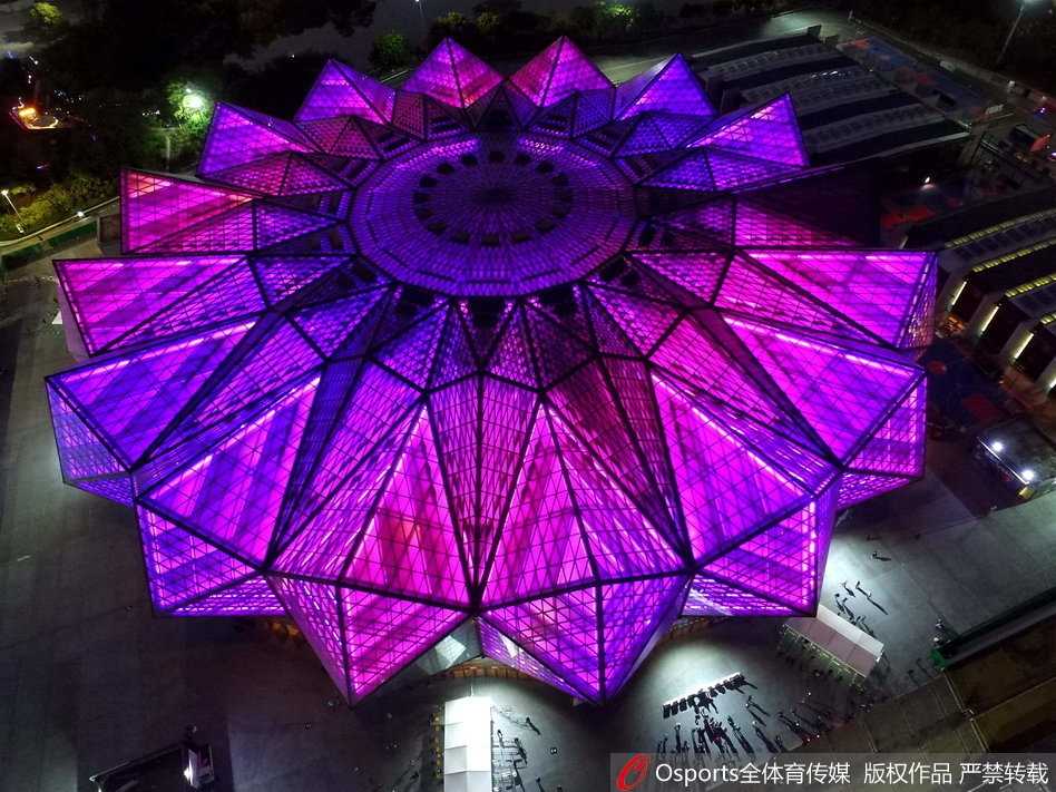 璀璨夺目的深圳龙岗大运中心体育馆，在深蓝色夜幕下通体透亮，犹如一块被精心雕琢的巨型水晶，映射出迷人的光影。