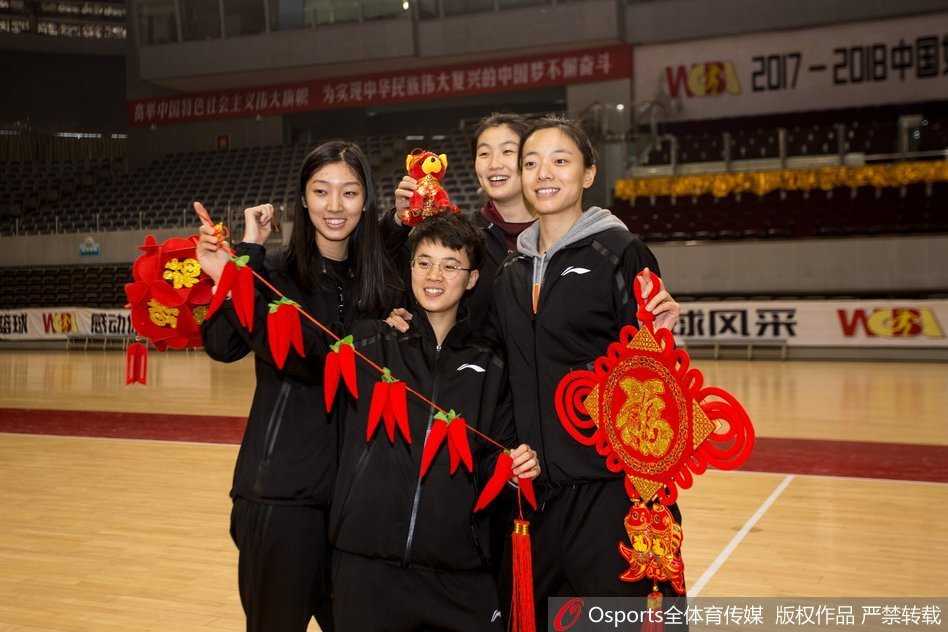 队员们对着镜头比出“耶”的手势，有人拿着春联，有人拿着福字，背景中红色与金色的装饰交织，整个画面洋溢着青春与活力的气息。