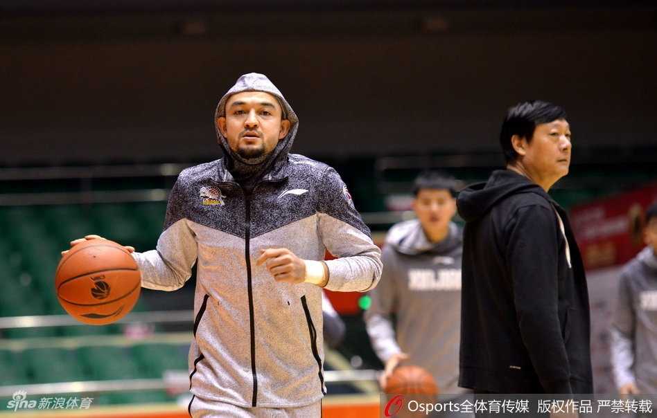 天山雄鹰蓄势待发:可兰白克领衔新疆男篮赛前冲刺,剑指泉城关键一役 拉伸放松时刻,可兰白克坐在地板上,平静地望向远处,背景是空旷的球馆和队友模糊的身影,此刻的宁静预示着不久后即将在这里掀起的惊涛骇浪。