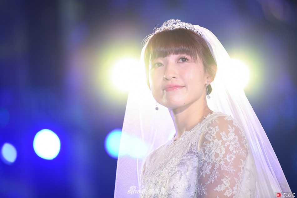 女篮名将杨半伴大婚:从球场“变速器”到人生新赛场 杨半伴与身穿灰色西装的丈夫甜蜜相依,新娘手捧红色玫瑰,新郎轻挽她的腰肢,画面充满了新婚的甜蜜与温馨。