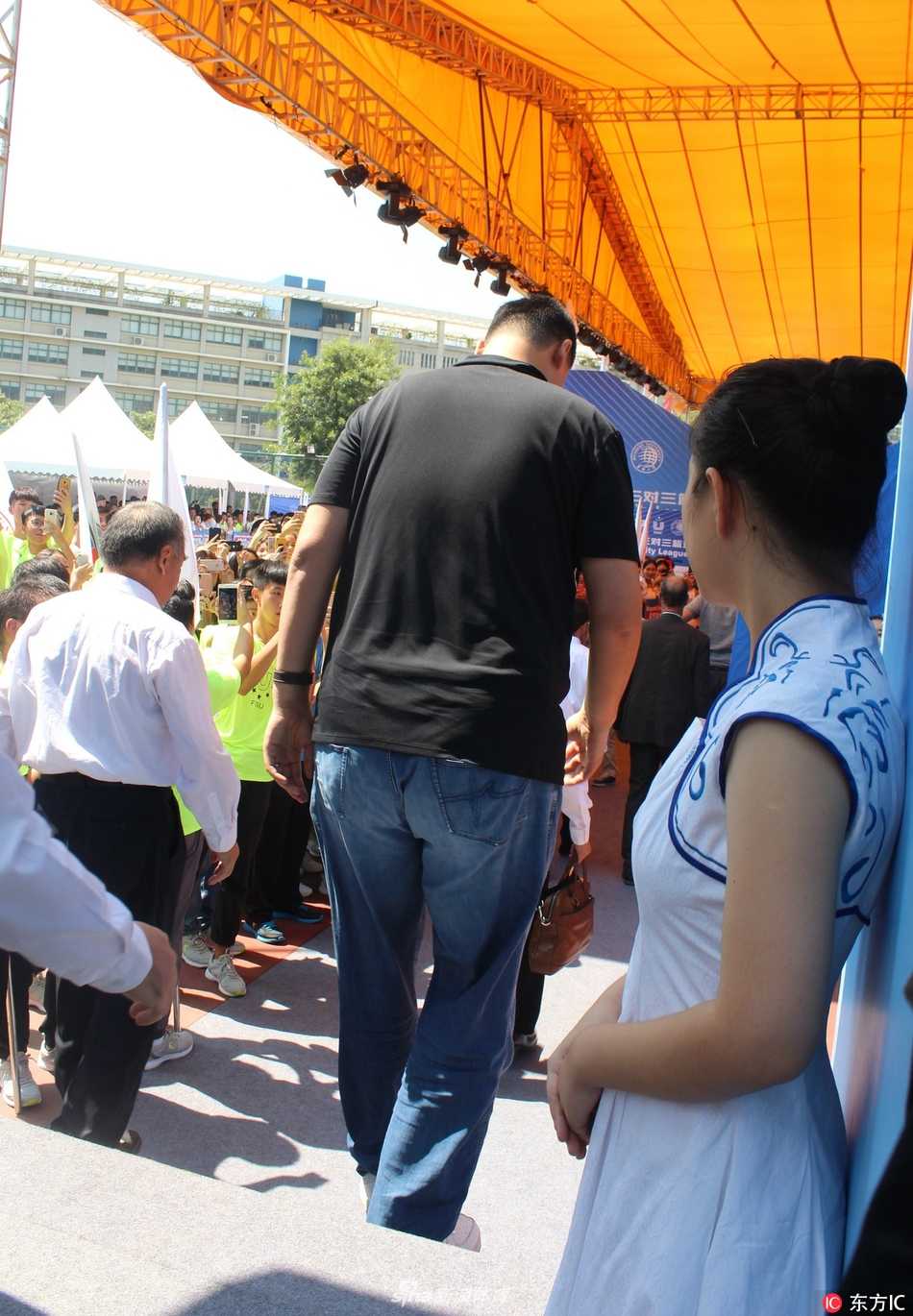 姚明端坐在看台上专注观赛，周围是热情的大学生们，他的目光紧紧跟随着球场上的攻防转换，仿佛也在回忆自己曾经在赛场上的峥嵘岁月。