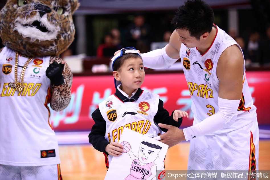 孟铎在比赛中运球突破，身形矫健，他的眼神坚定，场边的观众席虚化为背景，这一刻的拼搏精神，正是他想通过签名球衣传递给轩轩的力量。