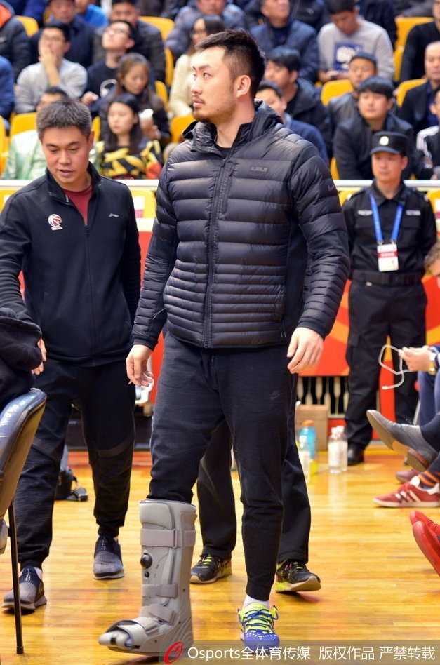 带伤观战神情凝重 睢冉缺阵山东加时险胜广厦 睢冉在场边专注地看着比赛,他的侧脸线条硬朗,下巴上蓄着标志性的胡须,身后的看台上坐满了热情的山东球迷,大家的目光都聚焦在场上,而睢冉的脚伤让他只能静静地坐着。