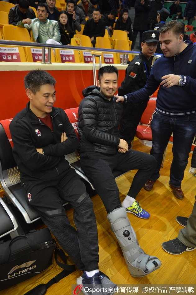 带伤观战神情凝重 睢冉缺阵山东加时险胜广厦 睢冉在场边观战,他双手撑在膝盖上身体前倾,目光紧紧跟随球场上的快攻身影,左脚的护具在昏暗的灯光下显得尤为突出,仿佛诉说着他此刻的无奈。