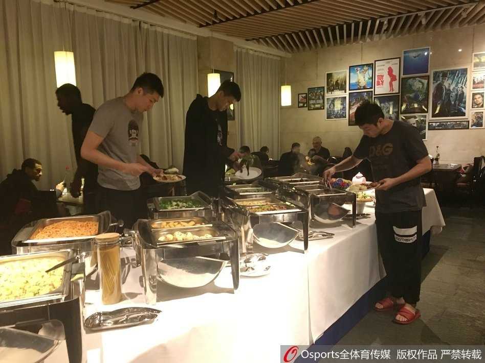 灯火通明的自助餐厅内，广东队的队员们正端着餐盘挑选各自喜爱的食物，场面温馨而有序。