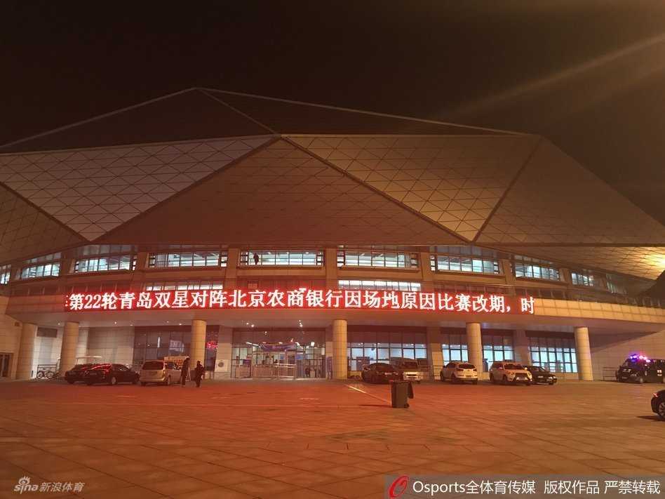 两名穿着制服的保安人员双手背后，面无表情地站在关闭的体育馆入场闸机前，原本应该检票入场的通道空无一人，只有他们守护着这个异常安静的比赛之夜。