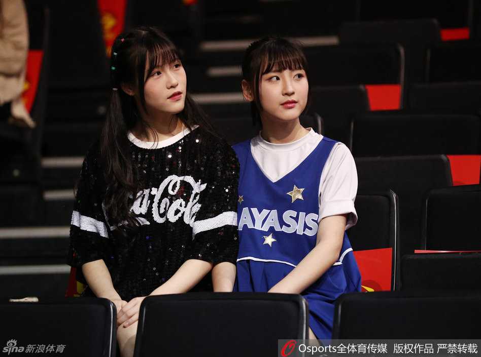 这位扎着双马尾的成员回眸一笑，眼神清澈明亮，手中的加油棒似乎在下一秒就会随着比赛的节奏舞动起来。