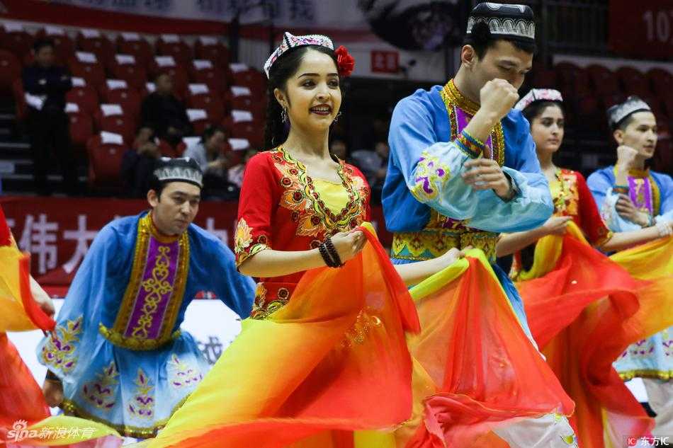 喀什市歌舞团的演员们手持传统花伞道具，在赛场上排列整齐，动作优雅划一