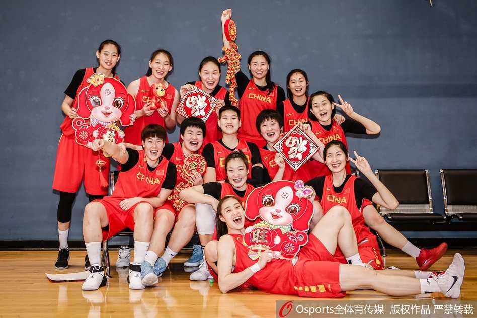新春闪耀映红光,女篮精神铸辉煌 身穿火红国家队队服的女篮姑娘们站成一排,对着镜头比出可爱的“666”手势,身后的新春装饰映衬着她们灿烂如花的笑容,洋溢着青春的朝气与节日的喜庆。