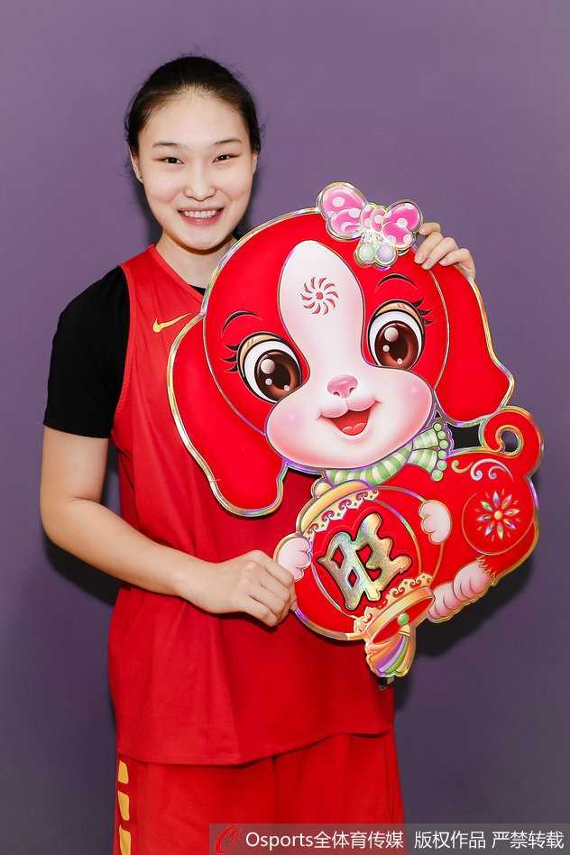 新春闪耀映红光,女篮精神铸辉煌 队员们围坐在一起,手中拿着红包和春联,背景的红色与中国女篮的队服交相辉映,画面充满了温馨的大家庭氛围,每个人的脸上都写着对未来的憧憬。