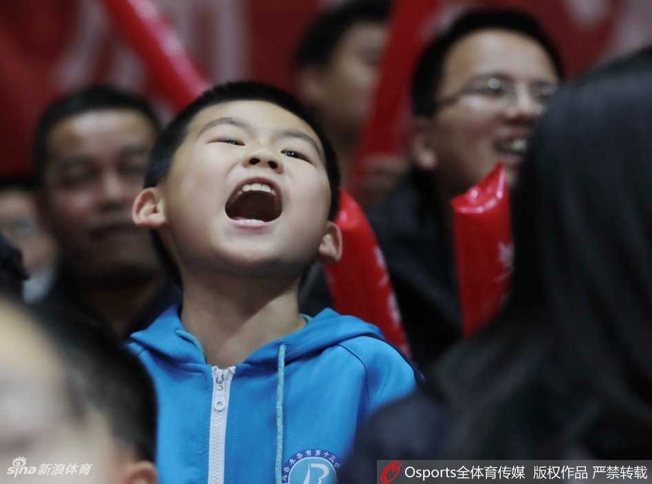 比赛暂停间隙，这位美女球迷对着镜头露出甜美的微笑，身后是同样沉浸在热烈气氛中的观众席。