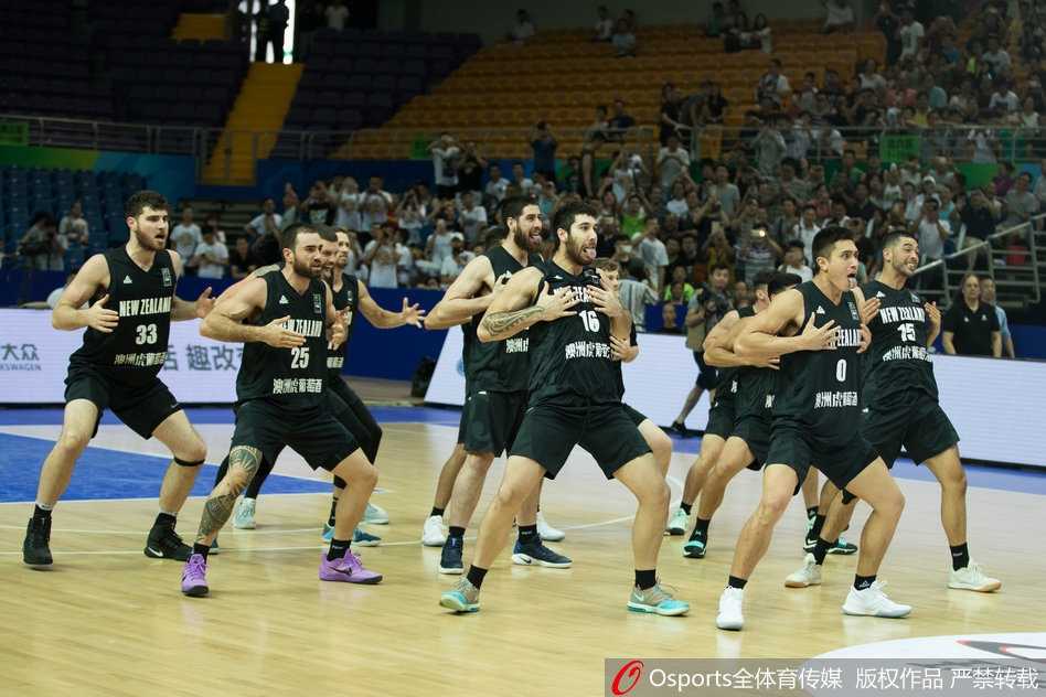 中国男篮蓝队的球员们站成一排，目光聚焦于对手的表演，神情专注而沉稳，虽然面对极具挑衅意味的舞蹈，但队员们保持了极高的职业素养和风度。