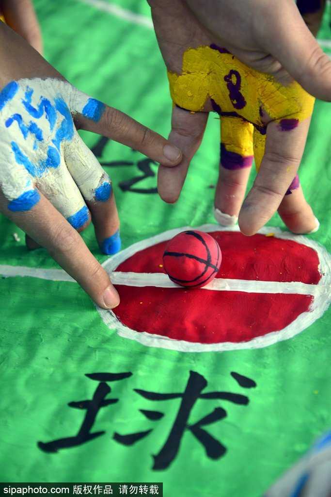 镜头拉近，可以看到‘球员’其实是用面团捏成的小人，安静地站在用纸板画成的球场上。而真正的‘运动员’——学生的手指，已经涂上了鲜艳的颜色，正准备登场，一动一静之间充满了童趣与想象力。