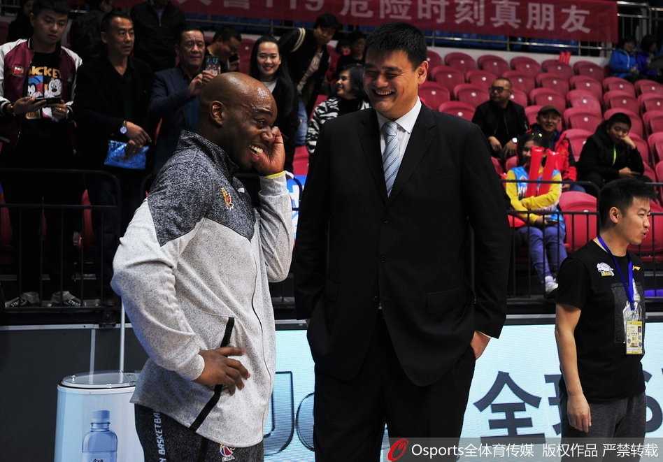 姚明与兰德里在CBA赛场重逢，两人面带笑容亲切交谈，仿佛有说不完的往事，眼神中满是老友重逢的喜悦。