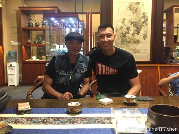 在餐厅一角，两人合影留念，阿联微微侧身照顾镜头高度，任达华则双手插袋，气定神闲，背后是都市璀璨的夜景。