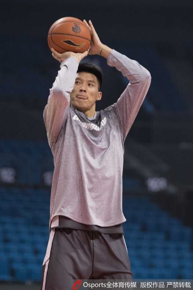 训练间歇，易建联拿起水瓶补充水分，汗水浸湿了球衣，但他的眼神依旧坚毅地盯着远处的篮筐。