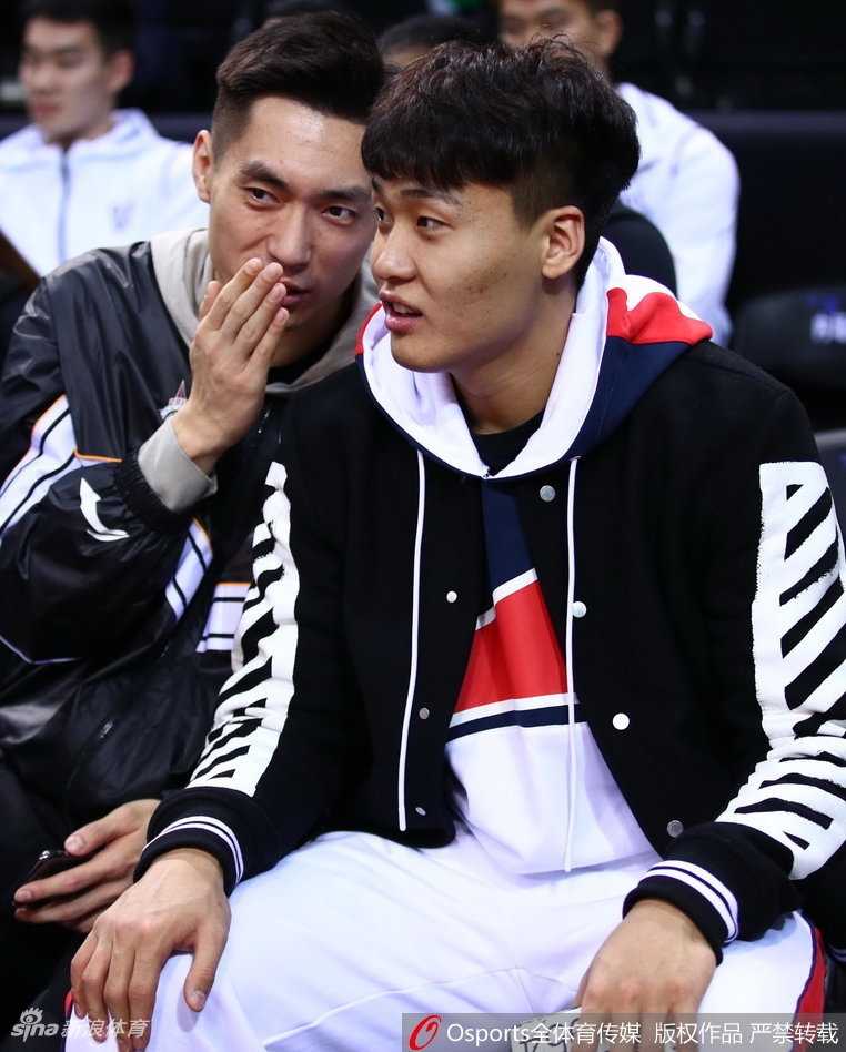 辽宁队中锋韩德君在看台上露出标志性的憨厚笑容，双手似乎正在为场上星锐球员的一次精彩配合鼓掌叫好。