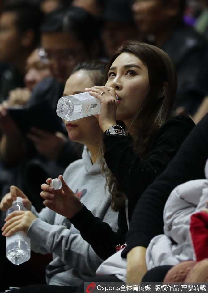 赛场边，她不经意间展露的甜美笑容与俏皮神态，与身后紧张观赛的球迷形成了鲜明对比。