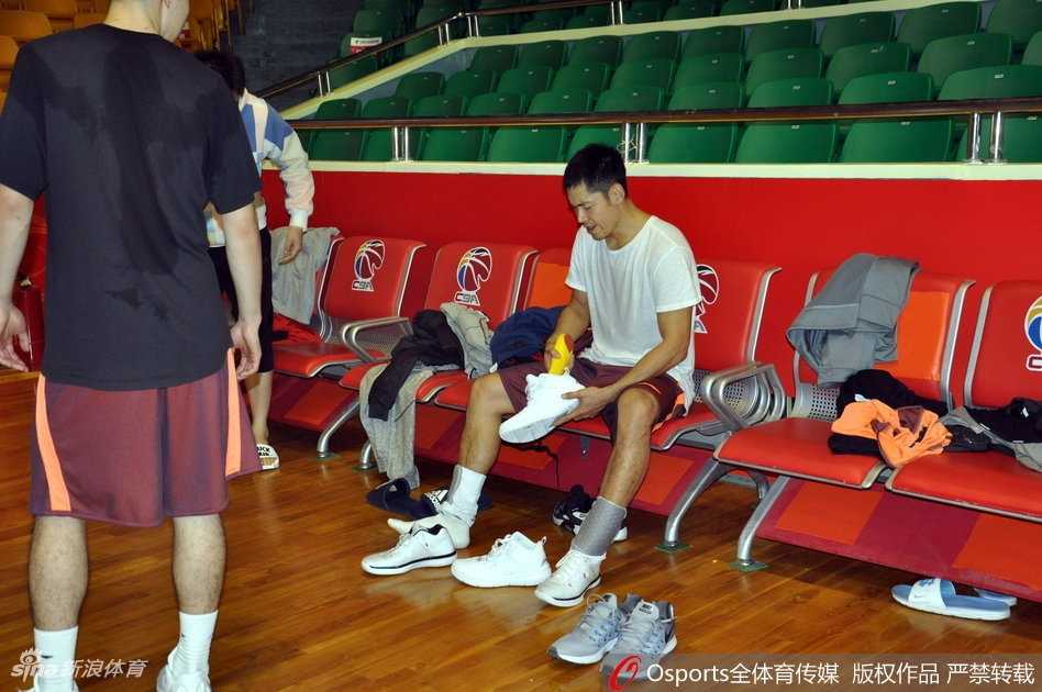 主教练邱彪在训练间隙为球员耐心讲解战术，手势坚定，神情严肃，队员们围成一圈认真聆听，团队凝聚力十足。