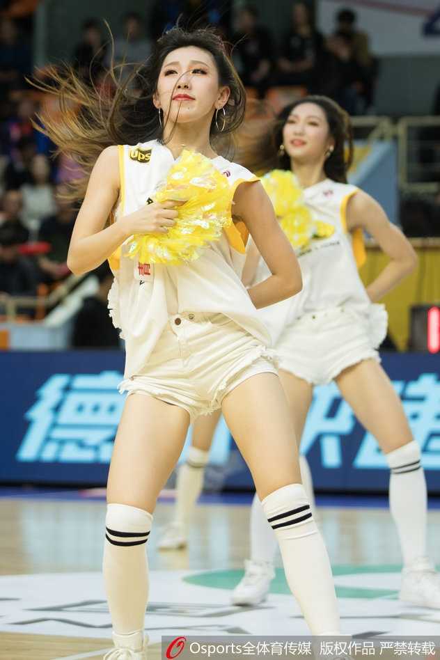 另一位篮球宝贝在表演中甩动秀发，手中的花球如同跳跃的精灵。她身穿亮片短裙，动作舒展而充满力量，展现出当代CBA篮球宝贝专业、自信的职业素养。