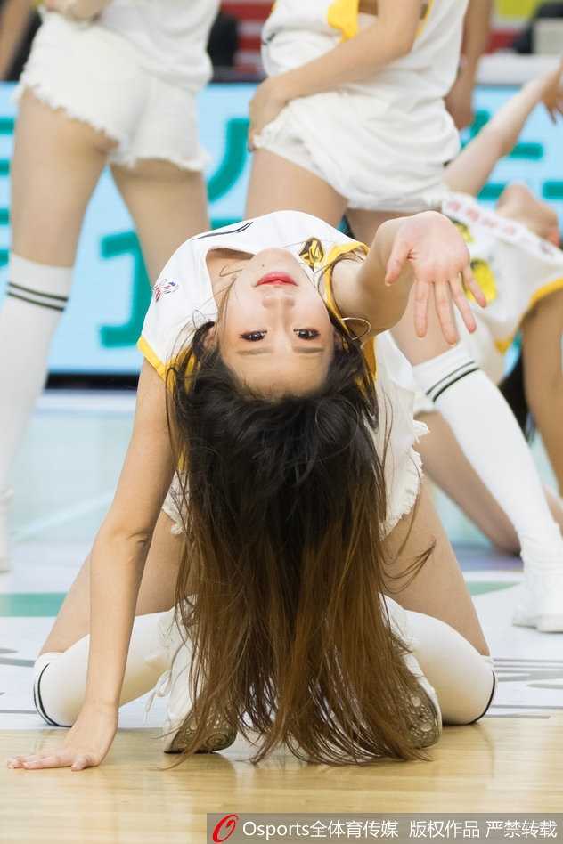 镜头拉近，一位篮球宝贝在动感的音乐中挥舞着金色的花球。她灿烂的笑容和专注的神情极具感染力，仿佛在用舞蹈的语言告诉观众，这里不仅是球员的战场，也是她们展现青春活力的舞台。