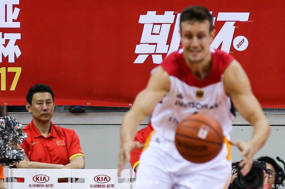 深圳夏夜的双雄会:斯坦科维奇杯德国战车碾过克罗地亚狂想曲,中国队静默观战 全景视角下,中国队的替补席沿着场边一字排开。红色的座椅、红色的球衣,构成一片红色的海洋。球员们的坐姿各异,但头部转向的方向惊人一致——都朝着球场中央。远处,德国与克罗地亚的球员正在拼抢,激烈的对抗与此刻场边的静态观摩形成鲜明对比,仿佛两个平行世界在这一刻通过篮球产生了交集。