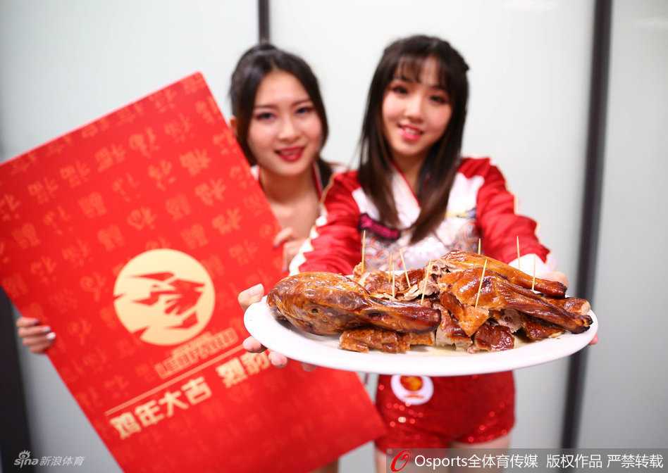 一位身材吸睛的篮球宝贝，手端一盘插着牙签的焦香烤鸭，对着镜头俏皮嘟嘴，眼神中满是邀请现场观众品尝的灵动。