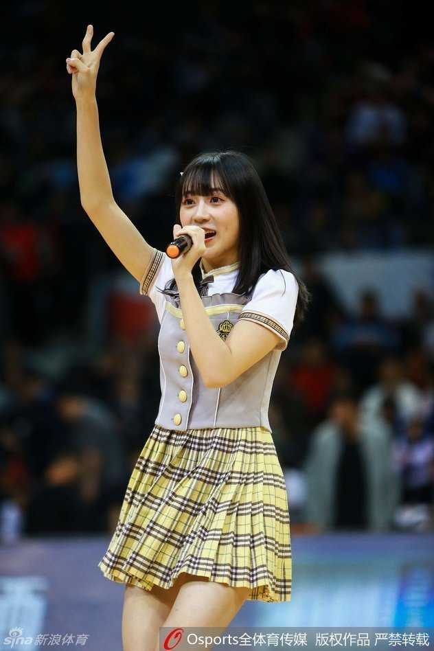一位扎着双马尾的成员正在压腿热身，认真的侧脸在赛场灯光的照耀下显得格外动人，尽显少女偶像的灵动与可爱。