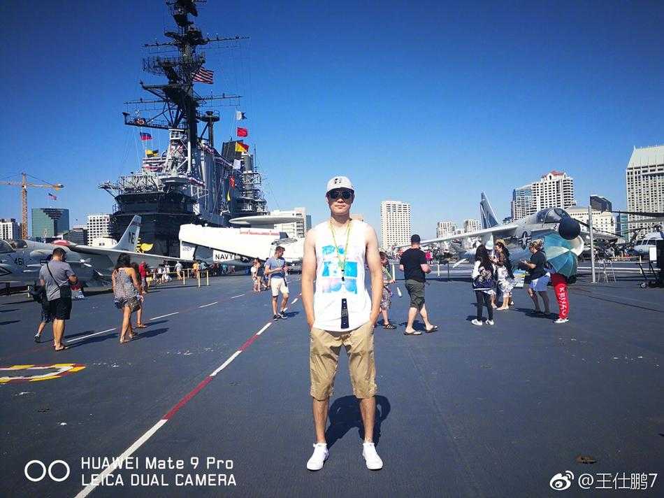 清晨的阳光为中途岛号航空母舰巨大的舰桥镀上一层金光，甲板上停满了各式战机，王仕鹏的背影显得既渺小又充满探索欲。