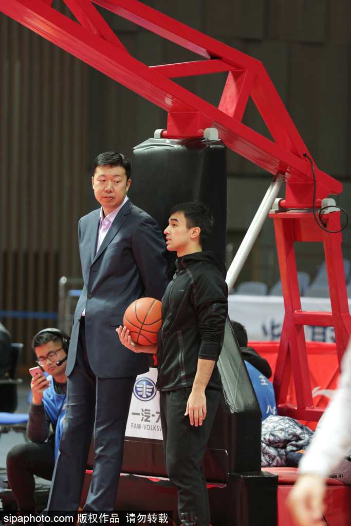 身穿蓝色卫衣的王治郅双手抱在胸前，目光专注如炬，仿佛要将场上每一位球员的热身细节都镌刻在心里，场边的他虽静默伫立，却自带一种定海神针般的气场。