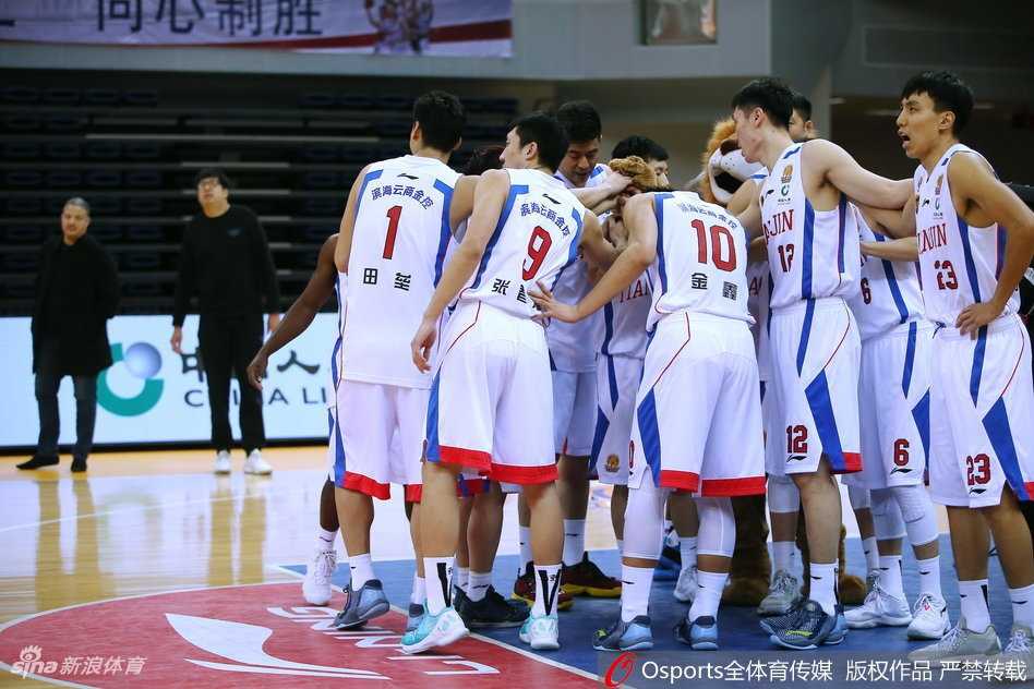 广厦队胡金秋在天津队内线长人阵中高高跃起，以一记轻盈的挑篮躲避封盖，眼神专注而坚定。