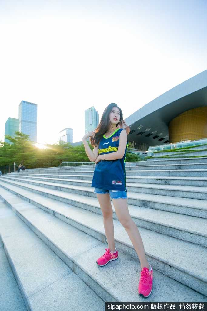 一位篮球宝贝双手指向镜头，神情俏皮又充满自信，身后的队友身影虚化，突显出她个人独特的青春魅力。