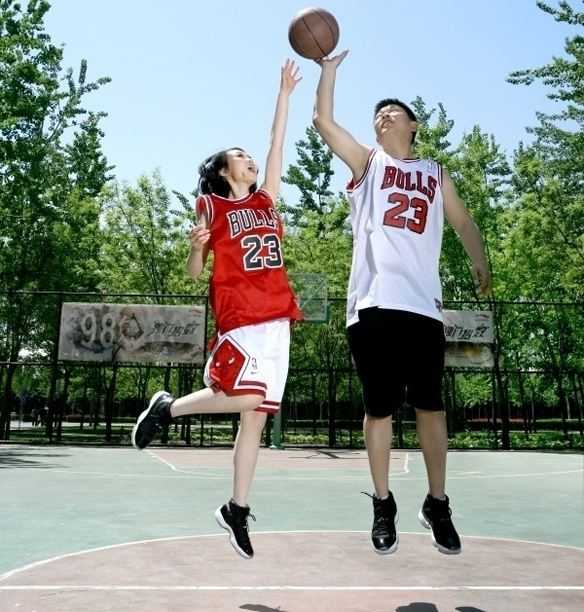 新娘穿着洁白的婚纱长裙，却在脚上搭配了一双运动鞋，她手持篮球调皮地指向镜头，身旁的新郎则一脸宠溺地注视着，画面充满了青春的俏皮与甜蜜。