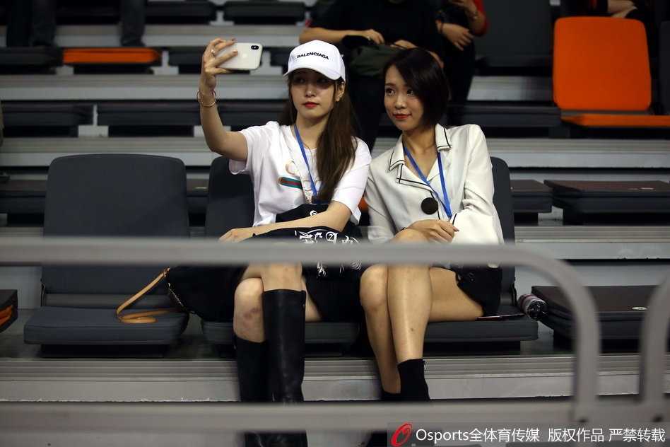 一位戴着时尚眼镜的美女球迷神情专注，双手轻轻托腮，在激烈的比赛间隙流露出别样的恬静与柔美。