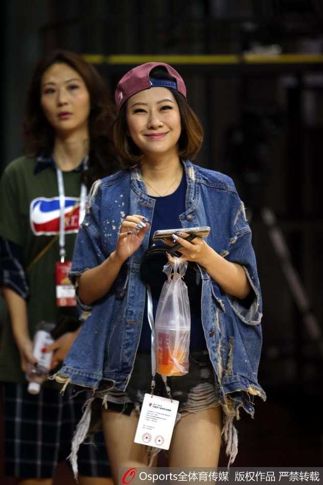 一位笑起来阳光灿烂的女球迷，对着镜头大方地展示着手中的助威棒，她的笑容为这场紧张的大战增添了无限暖意。