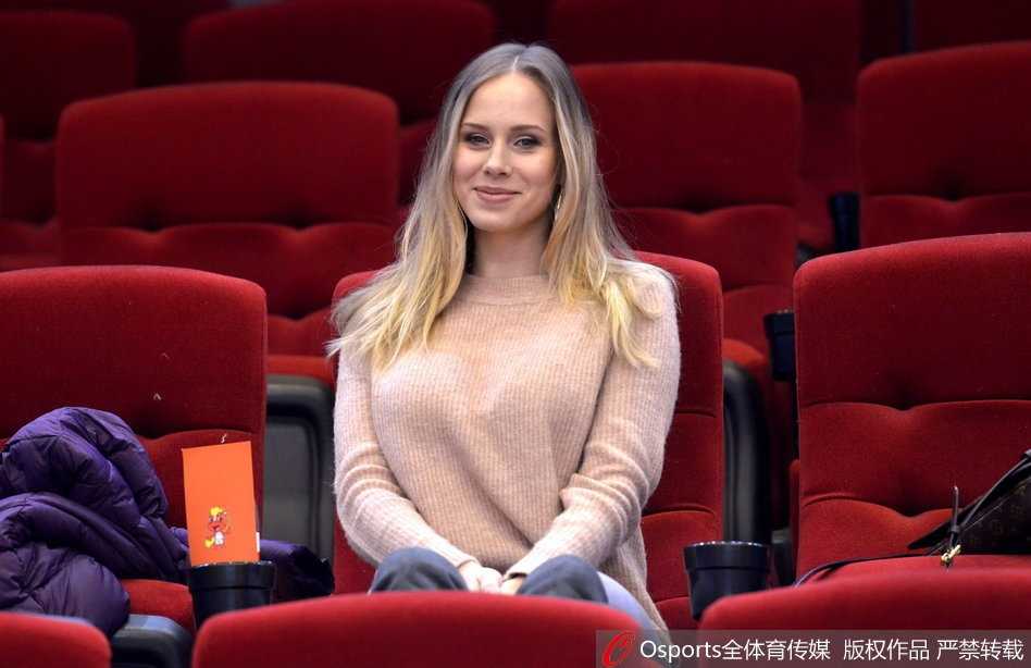 莫泰尤纳斯的妻子宝莲娜身着一袭休闲冬装，坐在山东队主场看台上，她目光温柔地注视着场内，为正在热身的丈夫默默祈祷与加油。