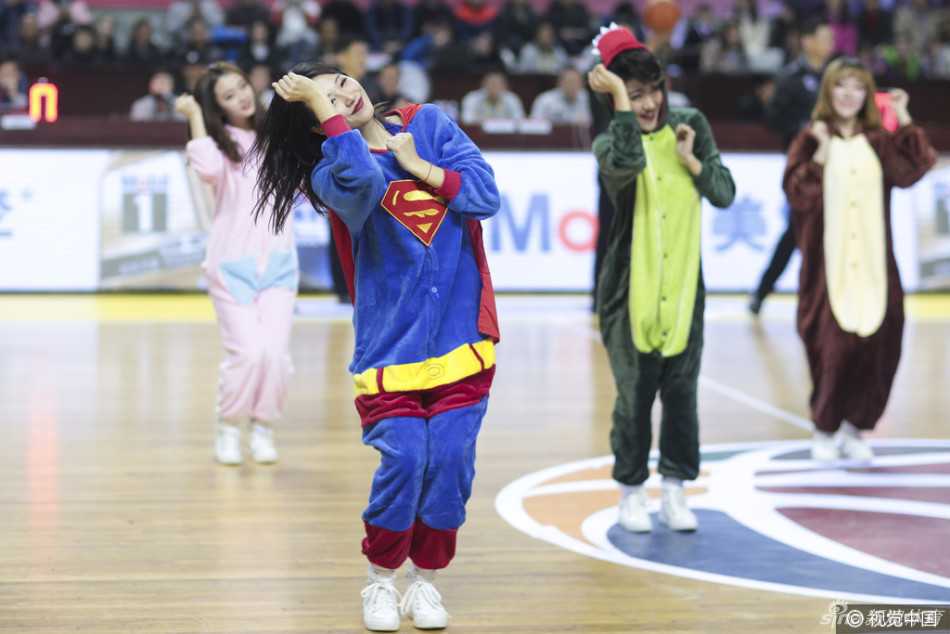 萌翻全场!当篮球宝贝变身睡衣女超人,赛场下的反差萌大作战 一名篮球宝贝穿着搞怪的恐龙连体衣,做出“起飞”的姿势,旁边的伙伴则模仿着开枪的动作,仿佛在玩“我们都是神枪手”的游戏,场面欢乐无比。