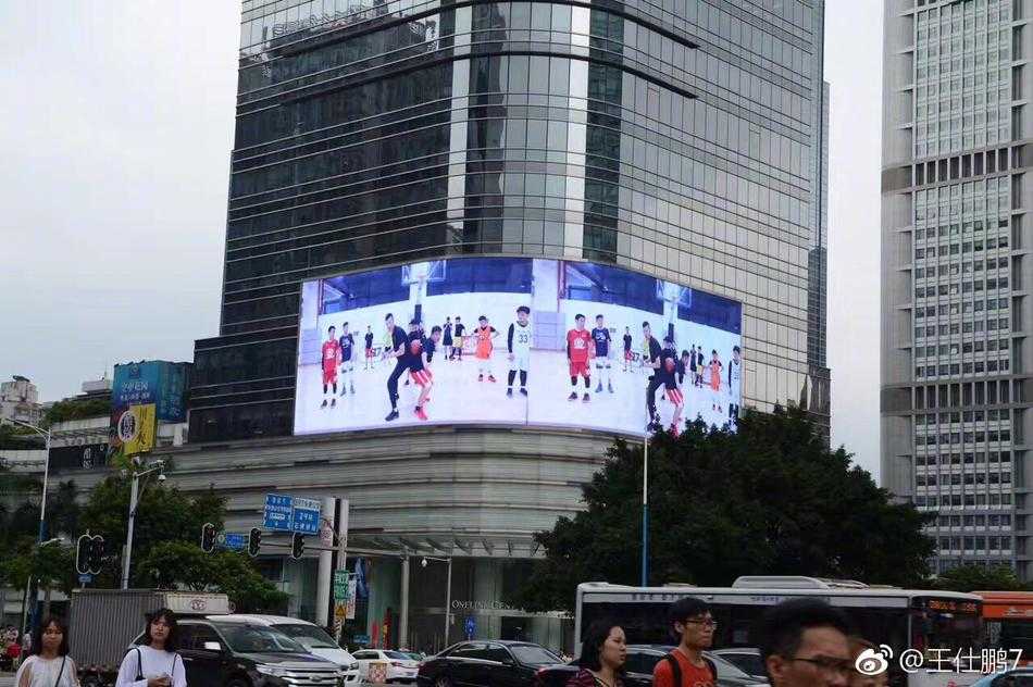 薪火相传,梦想不息:探寻身边易建联的篮球阵地 赛场上一位薪火小球员高高跃起投篮,汗水在空中飞扬,背景里是同样全力以赴的对手与充满期待的观众