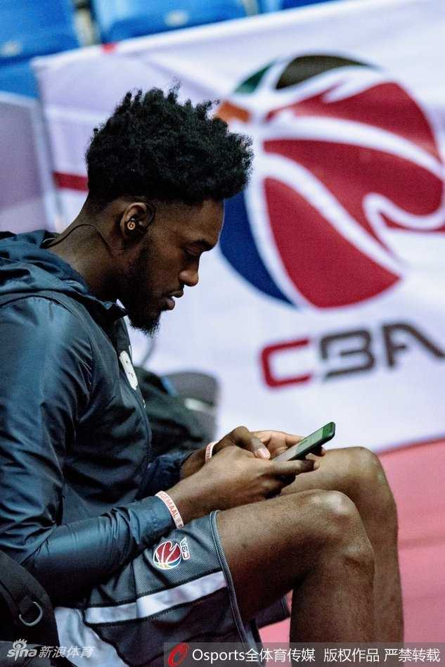 哈达迪在赛前训练中神情专注，双手捧着保温杯饮用热饮，眼神中透露着对胜利的渴望。