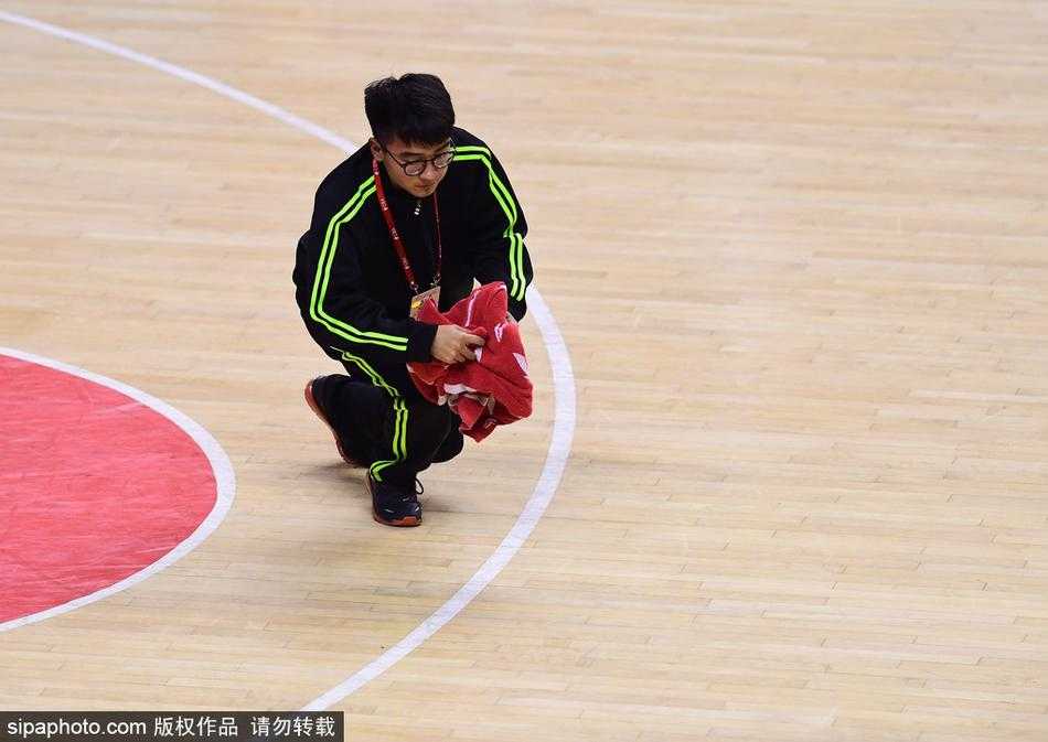 赛场边的“闪电侠”:CBA“地板工”的工匠精神与逆袭人生 裁判与球员围成一圈争球瞬间,场边穿着橙色马甲的“地板工”手持毛巾安静等待,随时准备履行职责