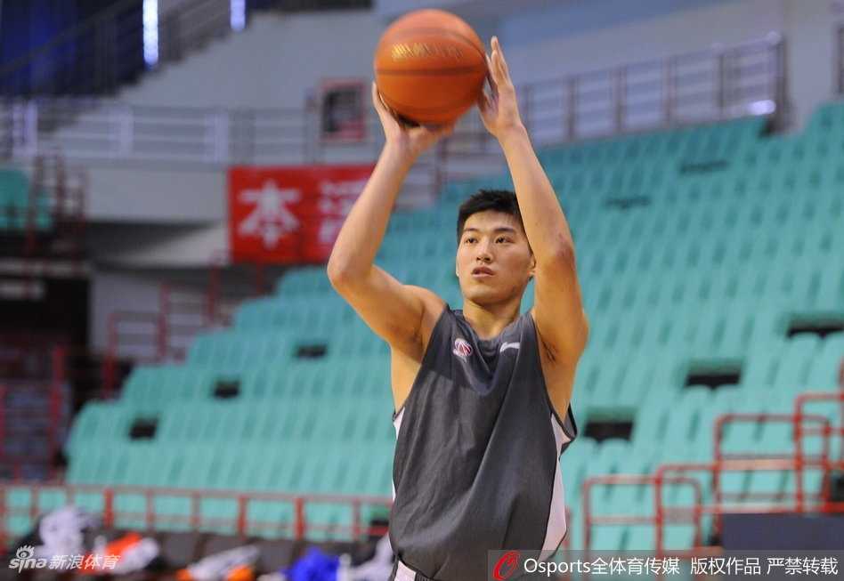 郭艾伦热身时与队友互动，他歪着头听队友说话，脸上露出略带狡黠的浅笑，画面充满兄弟情谊。