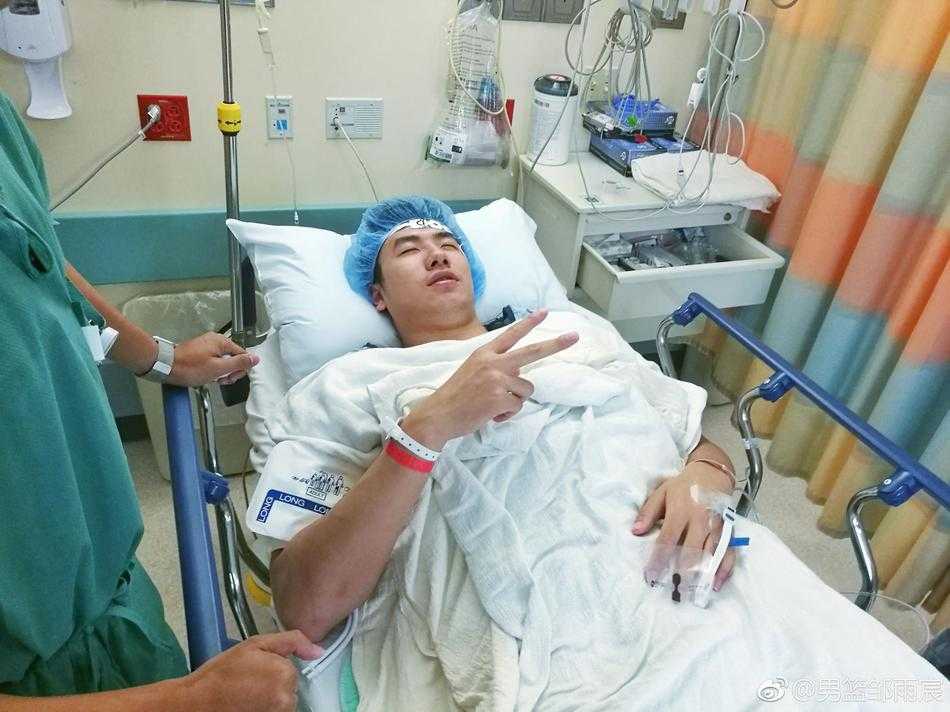 手术后的邹雨宸在病床前与医护人员合影，大家纷纷比出胜利的手势，气氛温馨而充满希望。