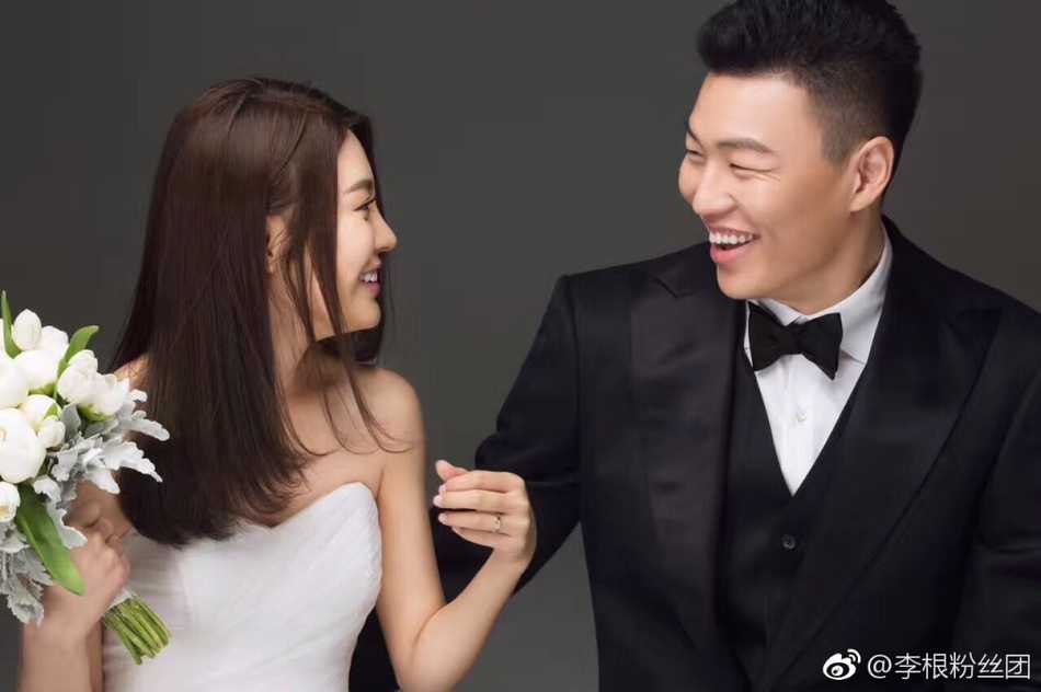 在一片温馨的布置中，李根与妻子轻松互动，背后是红色的国家队球衣，幸福的笑容在他们脸上洋溢，仿佛整个世界都为这份爱而静止。