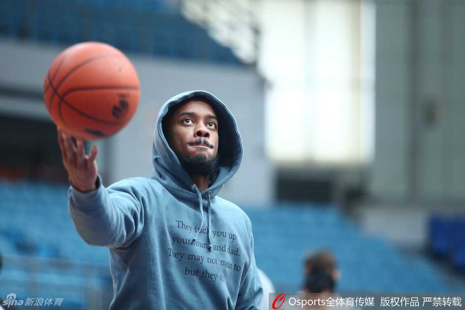 镜头下的篮球盛夏:布朗的专注与CBA众将的训练交响曲 身披休闲帽衫的杰伦-布朗坐在场边休整,目光如炬地瞄准远处篮筐,放松姿态中难掩专注杀气