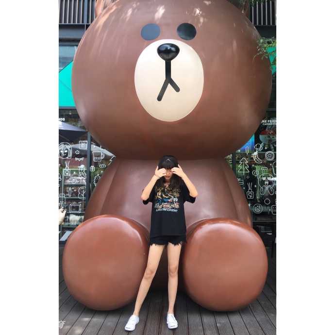 鲁西西ii在球场中线附近席地而坐，双腿自然伸展，背景的篮球架与她的笑容相映成趣，画面充满了故事感