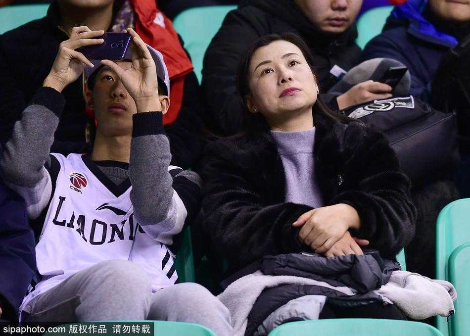 散场后的人流中，一位穿着貂皮大衣的球迷爸爸将孩子扛在肩上，孩子手里还拿着辽宁队的小旗子。寒冷的冬夜，父子的身影在路灯下被拉长，皮草的厚重与亲情的温馨交织，为这场篮球盛宴画上了一个温暖的句号。