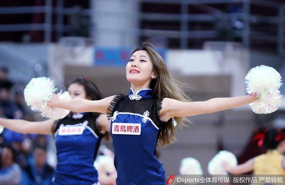 青岛篮球宝贝们背对镜头排成一排面向观众席热舞，台上摆满助威棒，台下观众视线被牢牢吸引，她们整齐划一的动作成为中场休息时的视觉盛宴