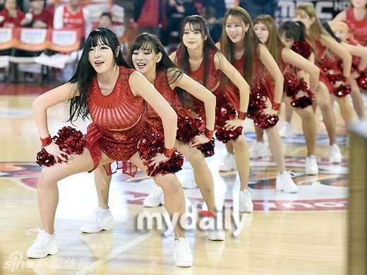 全景镜头捕捉到所有啦啦队员在场上散开的瞬间，她们身着红白相间的队服，动作舒展，仿佛一朵朵盛开在木质地板上的花朵，将空旷的球场装点得生机勃勃。